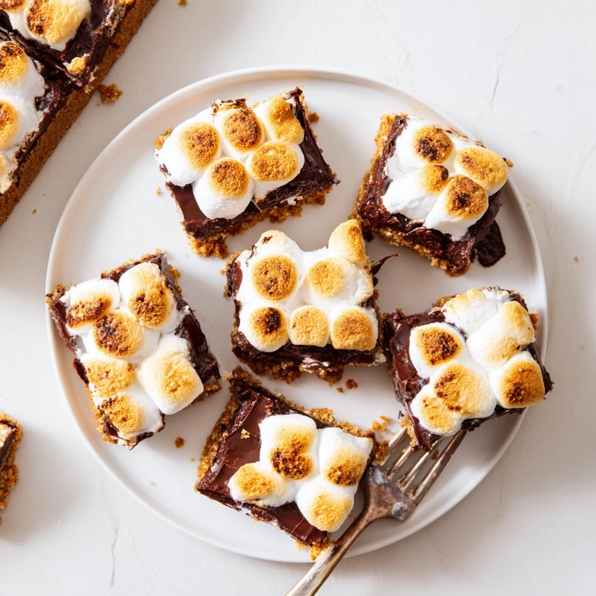 Freshly baked S'mores Bars are cut into squares, revealing a soft marshmallow and chocolate center.