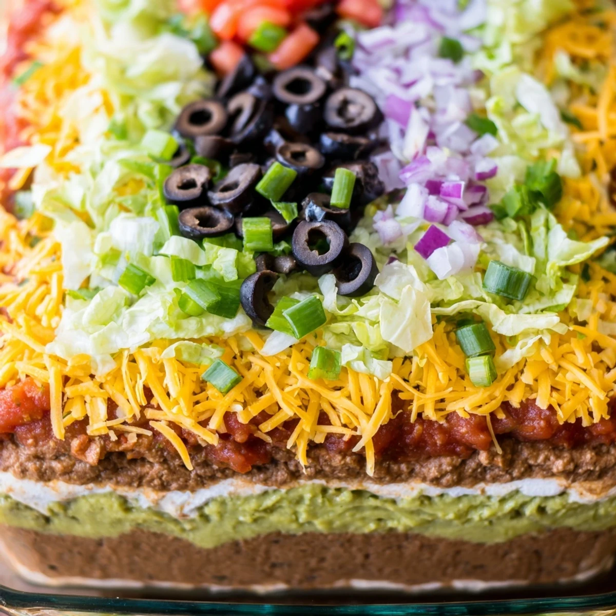 Seven-layer dip with creamy guacamole and sour cream, served with crispy tortilla chips for dipping.