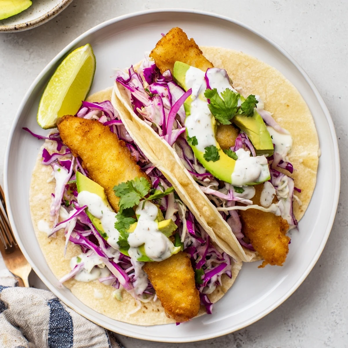 Restaurant-style Baja Fish Tacos with crunchy cabbage and zesty lime sauce, served warm and ready for a family dinner.
