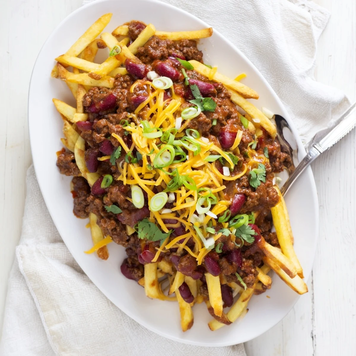 Golden Chili Cheese Fries topped with savory beef chili, melted cheddar, and fresh green onions.