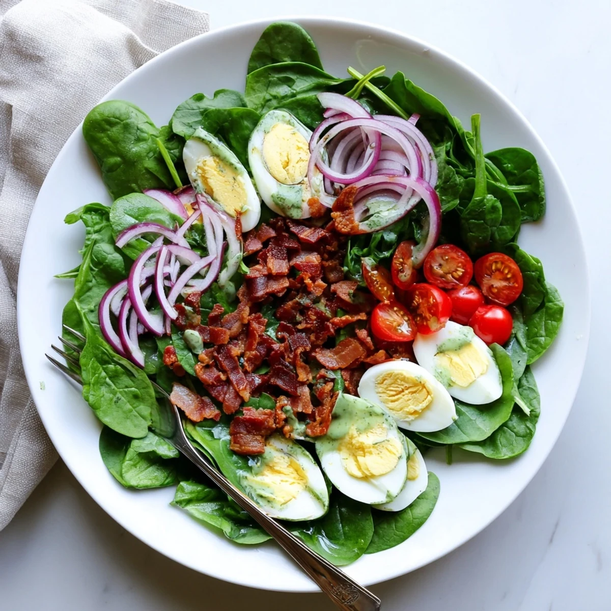 Fresh spinach and crispy bacon crumbles tossed with sliced boiled eggs in a tangy homemade dressing, served as a hearty lunch salad.