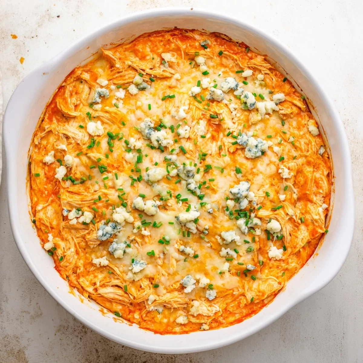 Golden bubbly Buffalo Chicken Dip fresh from the oven, featuring a cheesy top layer and specks of green chives.
