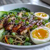 Savory Healthy Miso Chicken Noodle Bowls topped with soft-boiled egg halves, scallions, sesame seeds, and a drizzle of chili oil.