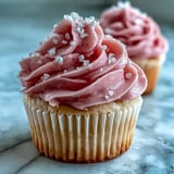 A close-up of Pink Velvet Cupcakes with creamy vanilla buttercream frosting and edible pearl decorations.