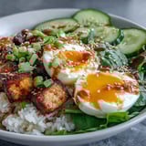 Close-up of Tofu Jammy Egg Breakfast Bowl drizzled with zesty ginger scallion sauce and garnished with fresh cilantro.