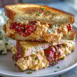 Delicate white bread finger sandwiches filled with classic Southern pimento cheese spread, garnished and ready for entertaining.