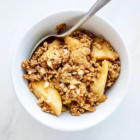 Homemade Apple Crumble served warm in a rustic dish, perfect with a scoop of vanilla ice cream melting on top.