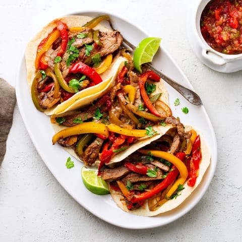 Skirt steak strips in Steak Fajitas, seared golden and paired with lime wedges and fresh toppings.