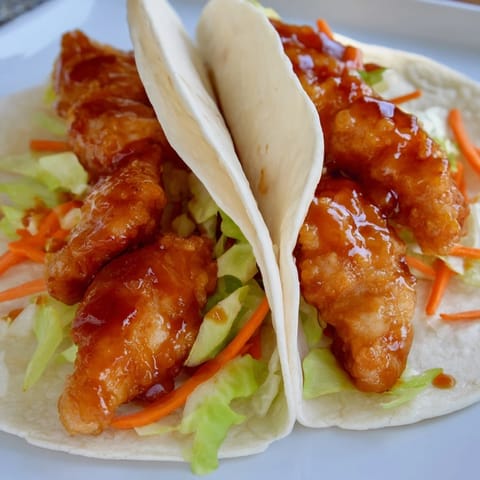 Fresh cilantro and red onion garnish the honey sriracha chicken wrap for a burst of color.