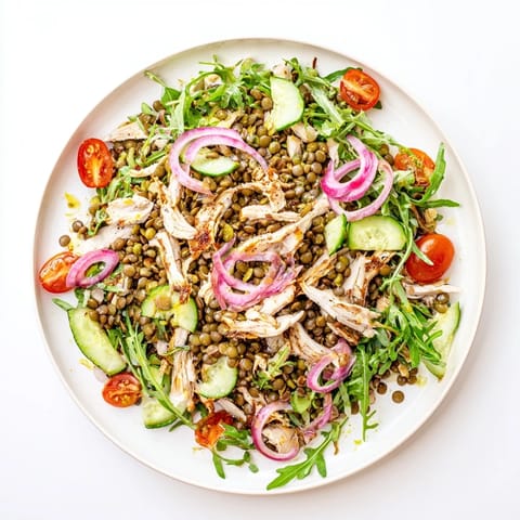 Top-down view of the Lentil & Chicken Spring Salad, featuring glossy pickled red onions, halved cherry tomatoes, and sliced cucumber on a rustic plate.