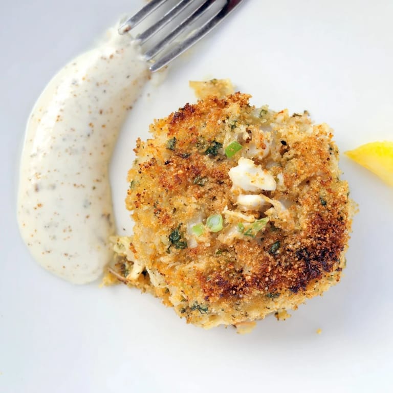 Close-up view of pan-fried Crab Cakes showing tender crab meat, herbs, and crispy panko crust.