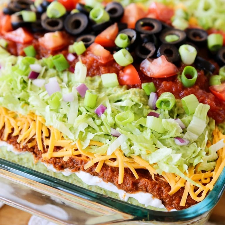 Chilled Tex-Mex seven-layer dip with black olives, salsa, and crisp lettuce, ready for a party.
