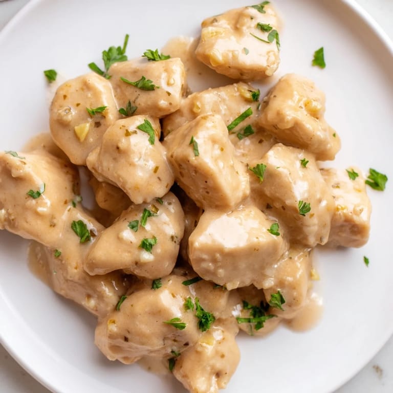Tender Creamy Garlic Chicken Bites served over steamed rice, drizzled with creamy garlic sauce.  