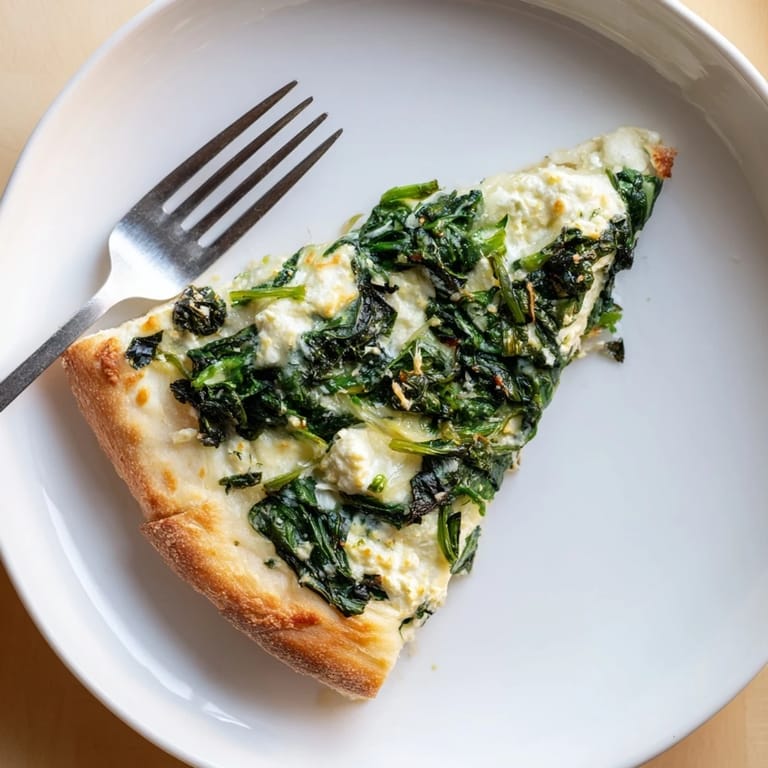 A golden Spinach Ricotta Pizza slice is lifted with a spatula, revealing melted mozzarella and garlic butter.