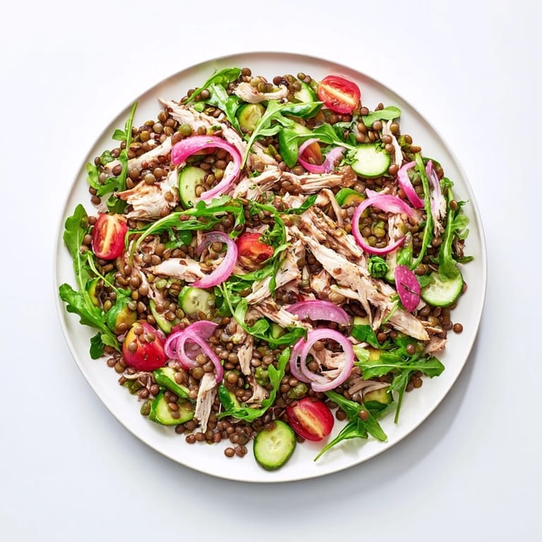 Freshly tossed Lentil & Chicken Spring Salad in a large bowl, showcasing shredded chicken and green lentils coated in tangy Dijon vinaigrette.